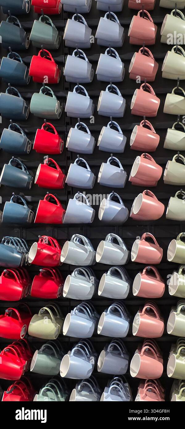 Colorful ceramic mugs are neatly arranged in a grid pattern, showcasing various hues and designs, creating a vibrant and inviting atmosphere. - Smartphone Captured Stock Image