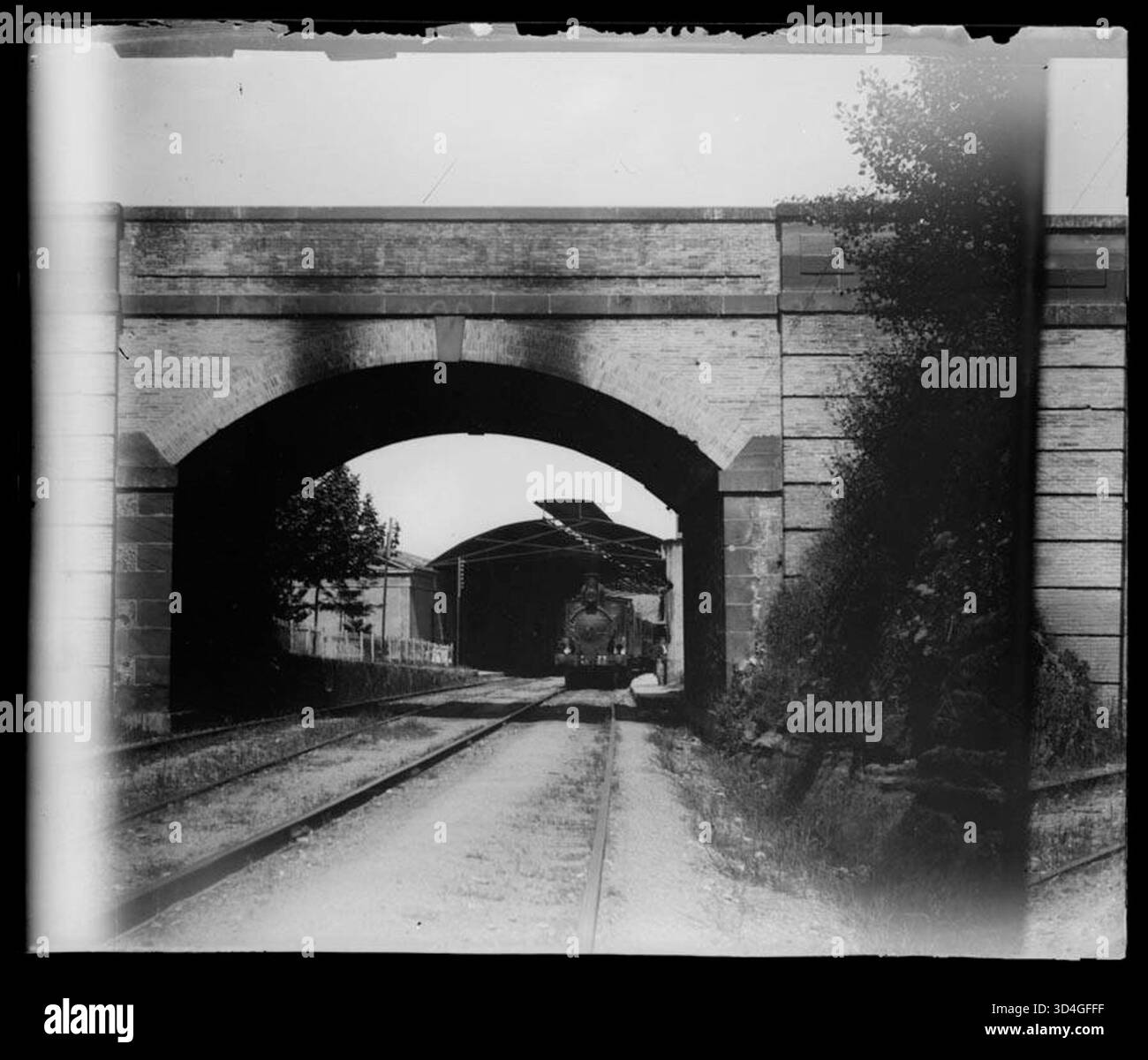 Rail tracks, a locomotive, and a train station with a bridge in the ...
