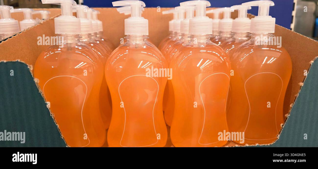 Clear plastic bottles filled with liquid soap are neatly arranged in a cardboard box, showcasing an organized product display for retail. - Smartphone Captured Stock Image