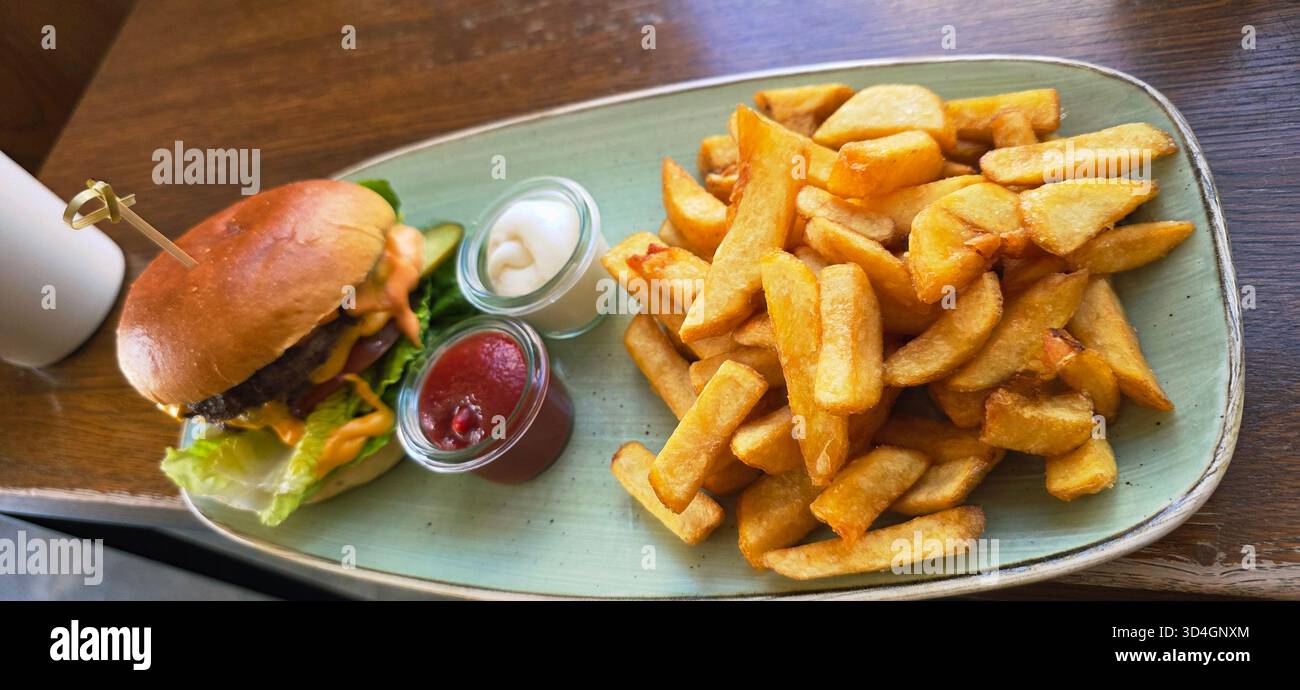 Gourmet burger with fresh ingredients, accompanied by crispy fries and dipping sauces, creating a mouthwatering dining experience. - Smartphone Captured Stock Image