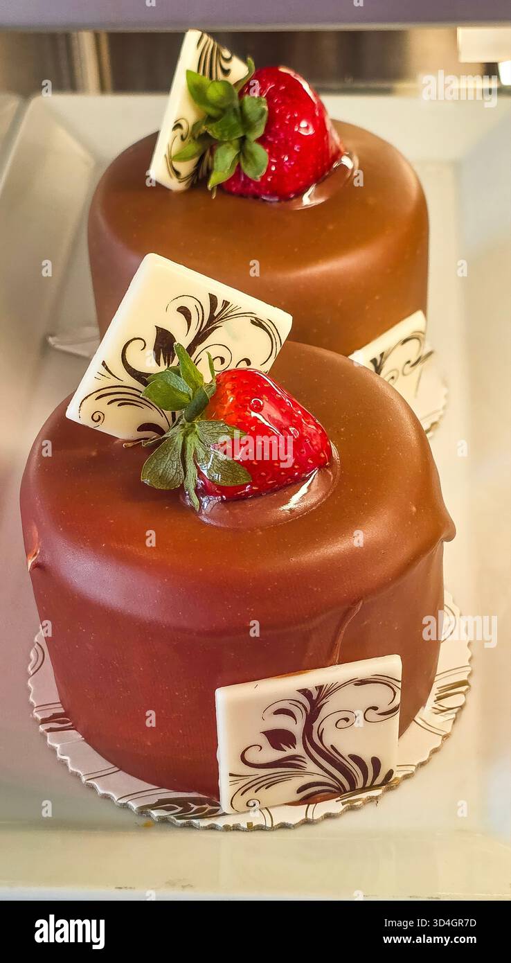 . Chocolate dessert cakes are beautifully topped with fresh strawberries and elegant decorative accents, showcasing a delightful culinary presentation - Smartphone Captured Stock Image