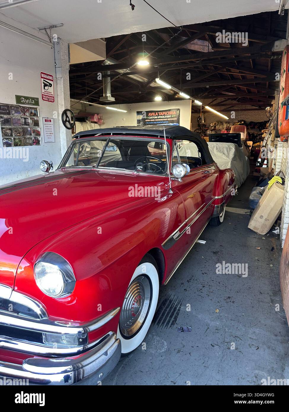 Red 1950s Pontiac convertible in auto upholstery workshop, California - Smartphone Captured Stock Image