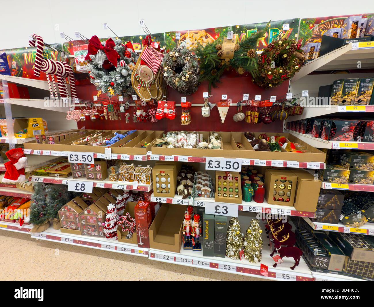 Tesco supermarket Christmas merchandising aisle with festive decorations, baubles, and holiday signage – UK retail display: Phillip Roberts - Smartphone Captured Stock Image