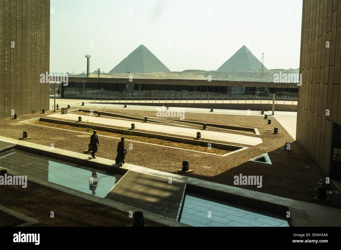Two cleaning workers pass by the side of the grand Egyptian museum ...
