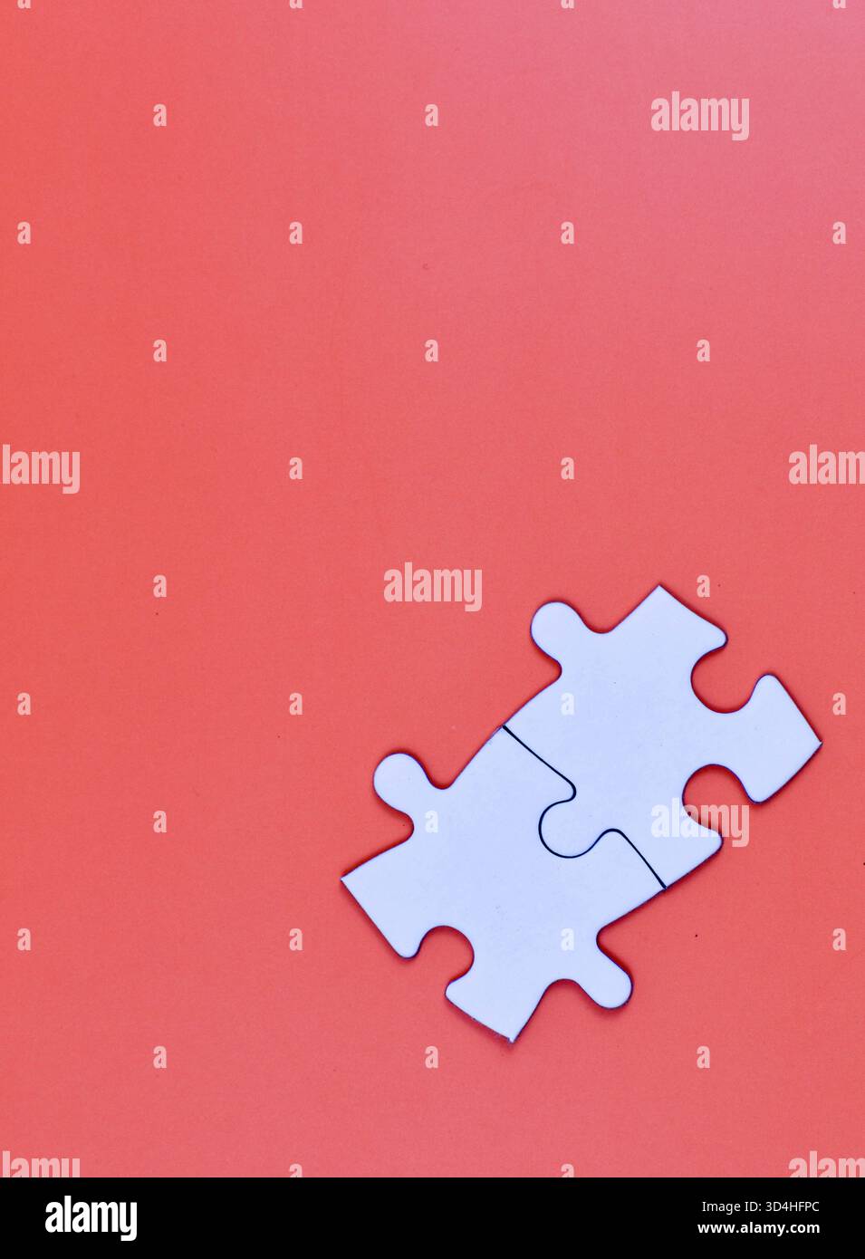 Two interlocked white puzzle pieces on orange background, symbolizing connection, unity, or problem-solving in a minimal visual composition. Stock Photo