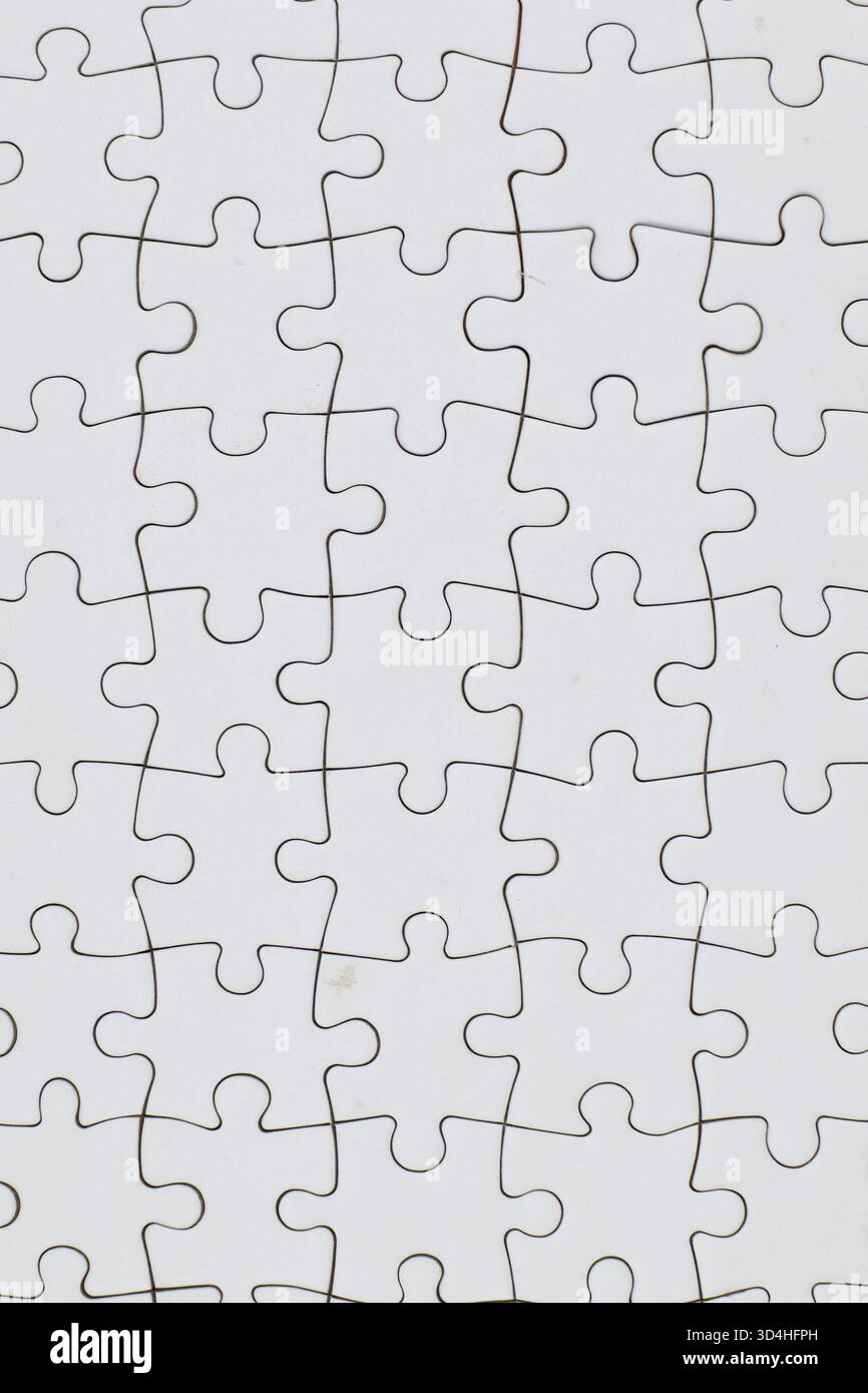 Blank interlocked jigsaw puzzle pieces arranged in grid pattern; uniform white surface emphasizes shape-based assembly challenge without visual cues. Stock Photo