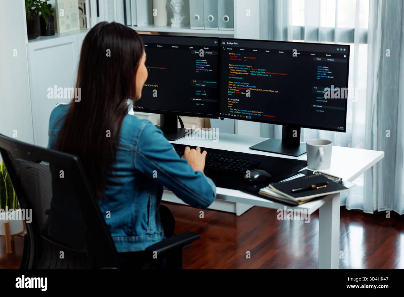 Young Asian in IT developer creating with typing online information on pc with coding program data of website application, wearing jeans shirt Stock Photo