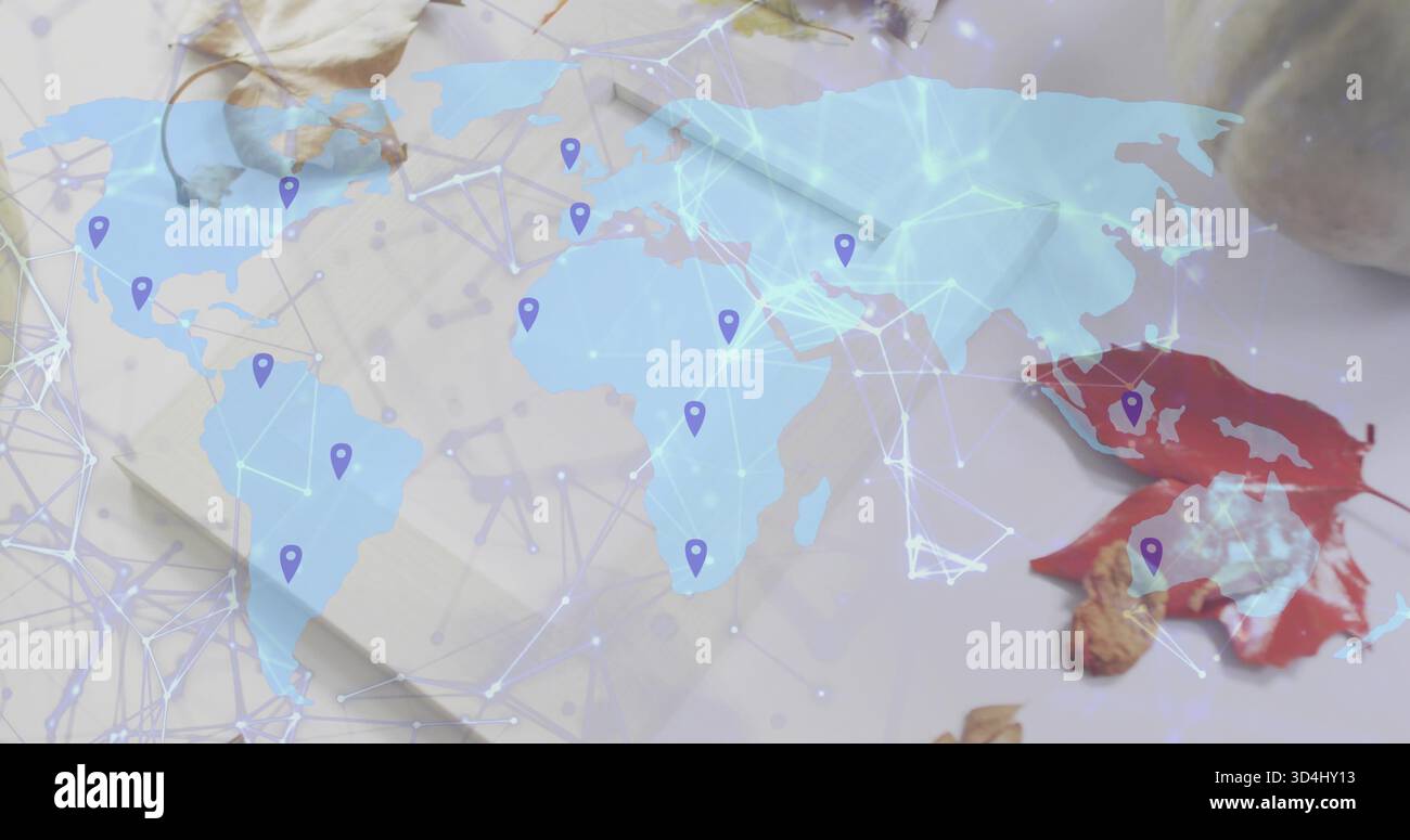 Showing translucent map across desk, displaying network lines, purple pins, notepad, red leaf, nut Stock Photo