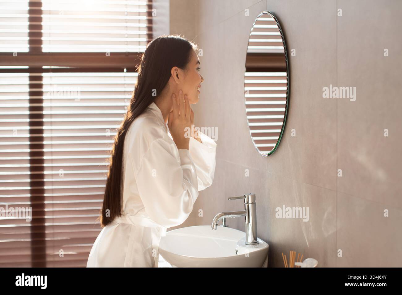 Korean Lady Admires Her Smooth Skin in Modern Bathroom During Morning Routine Stock Photo