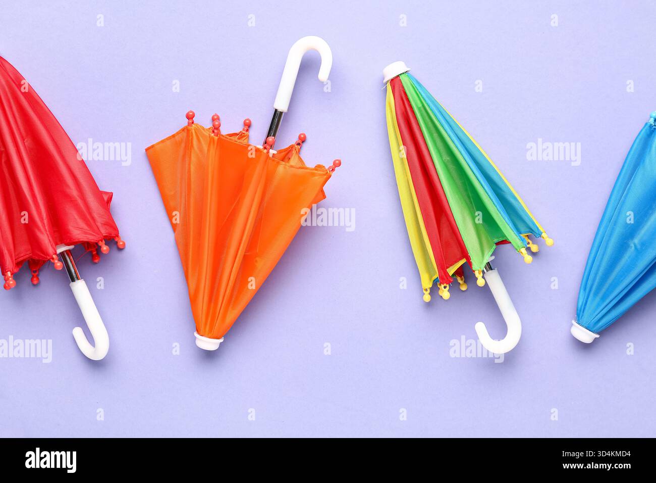 Mini stylish umbrellas on lilac background Stock Photo