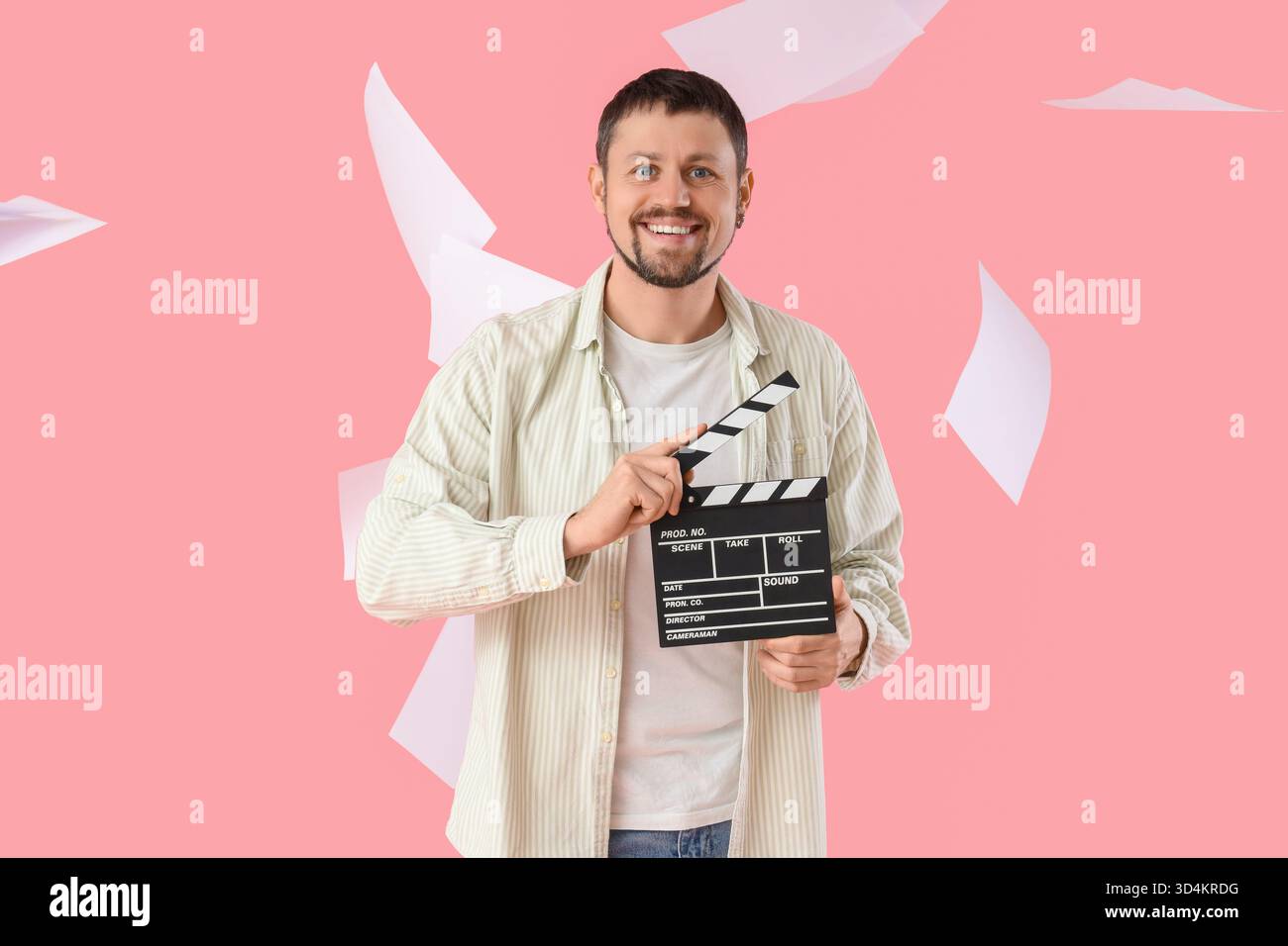 Male actor with movie clapper and falling film script on pink ...