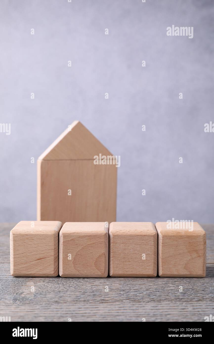 Blank cubes and house model on wooden table, closeup. Mockup for design ...