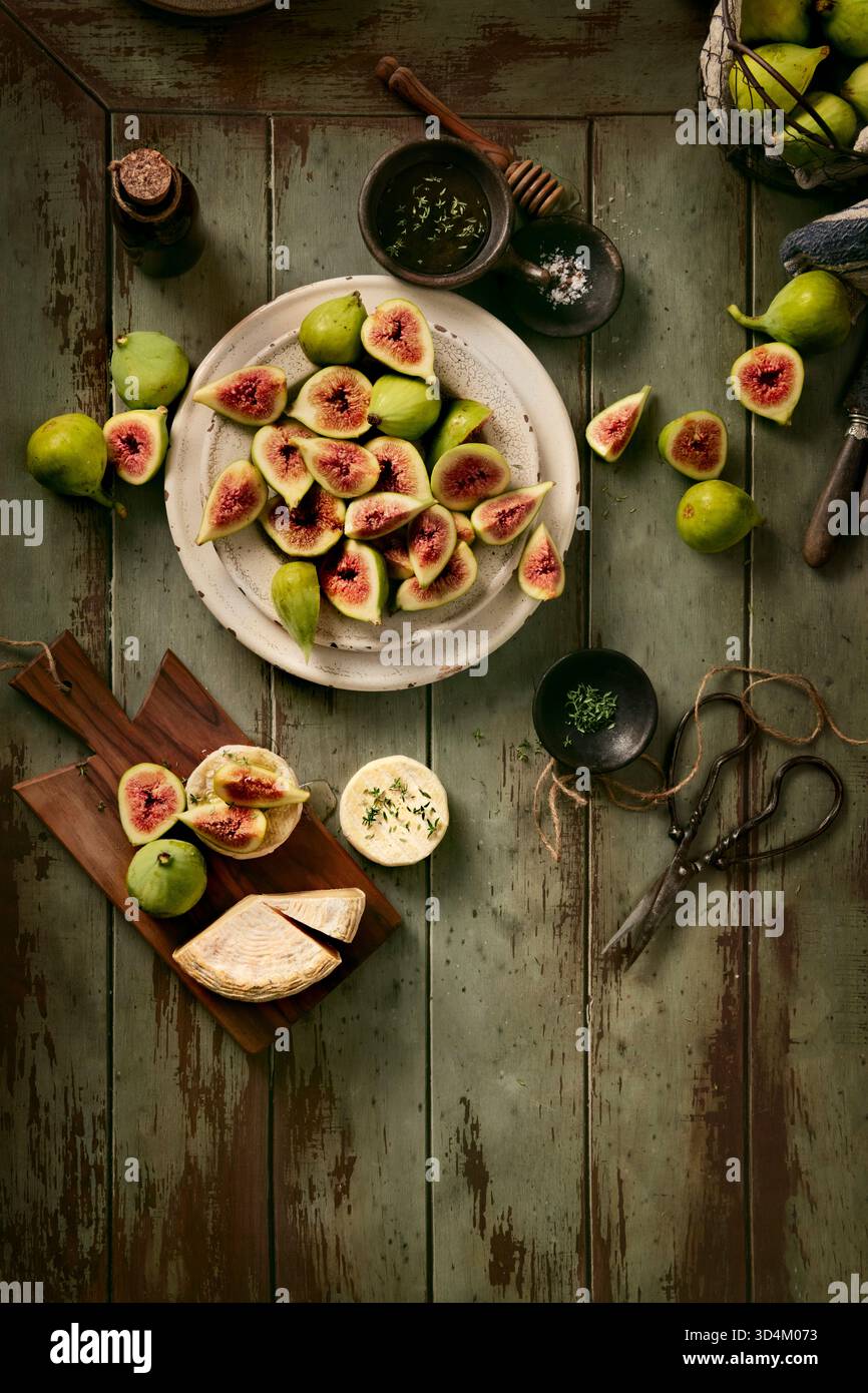 flay lay of ripe figs in plate and in a basket ready to eat with goat cheese and thyme honey, Stock Photo