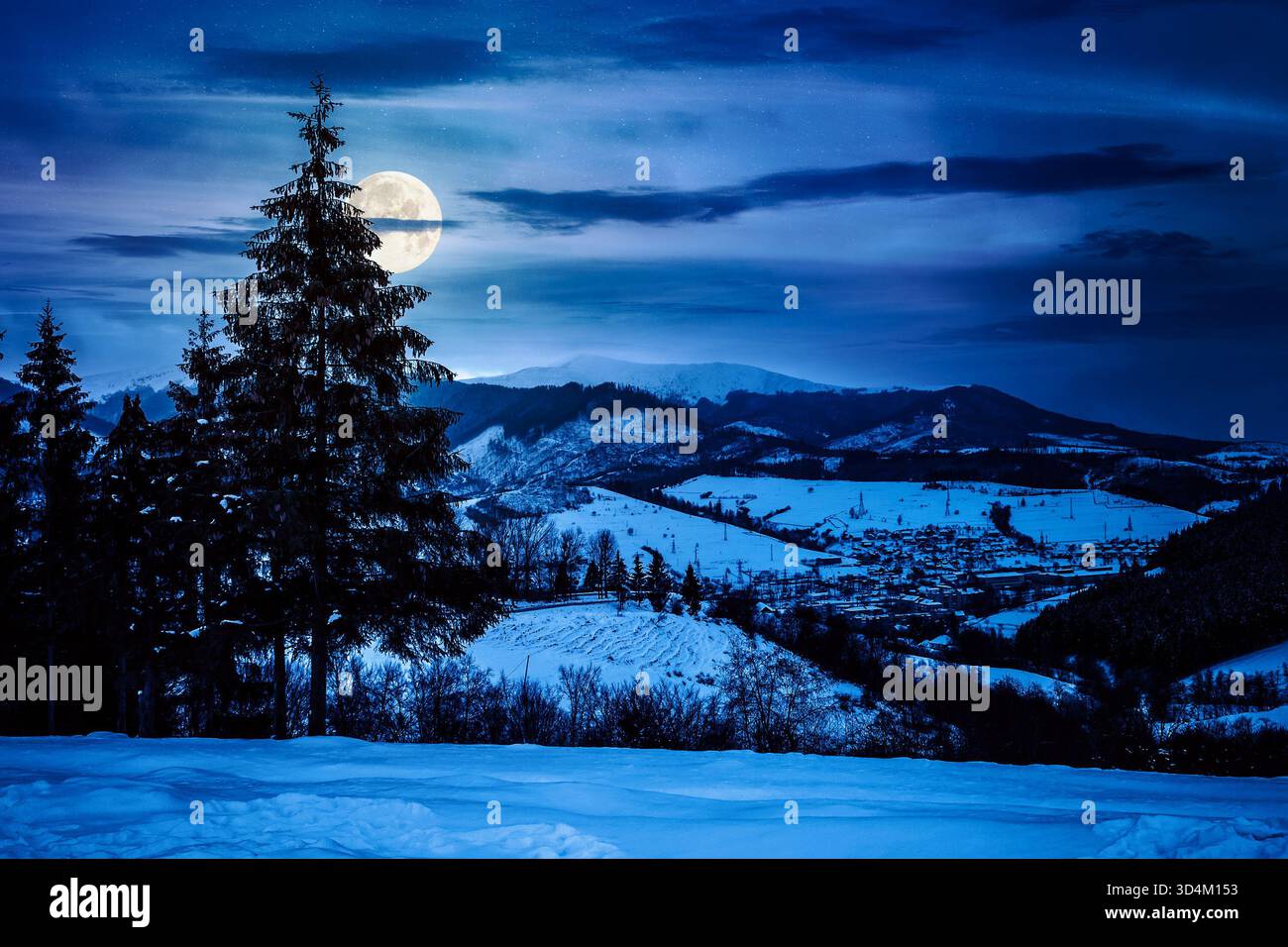 village in mountains at night. winter landscape covered with snow in full moon light. trees on rolling hills. background for investment or abstract co Stock Photo
