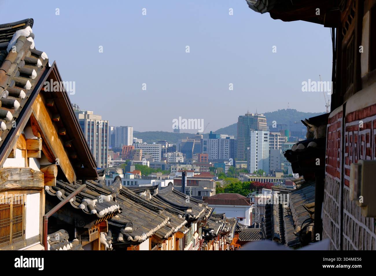 Traditional Hanok rooftops in Bukchon Hanok Village with modern Seoul ...