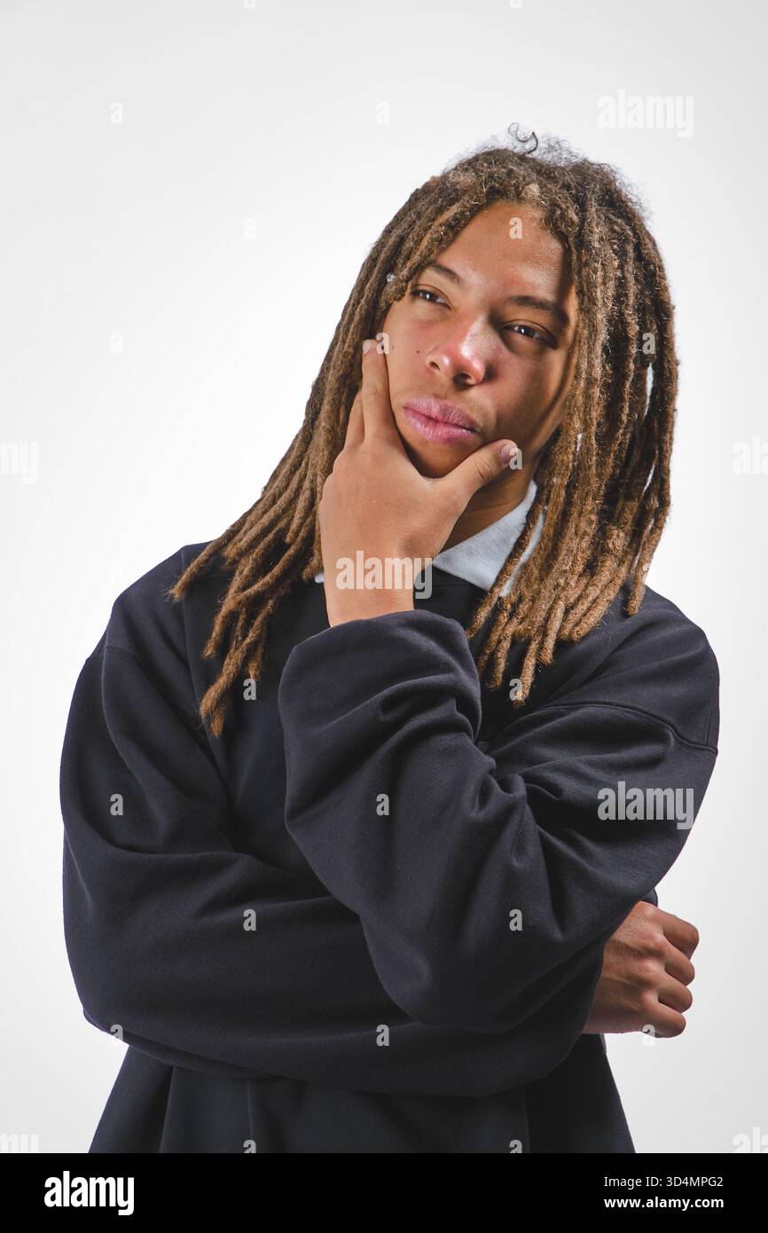 Young man with dreadlocks on a white background, contemplating thoughtfully Stock Photo