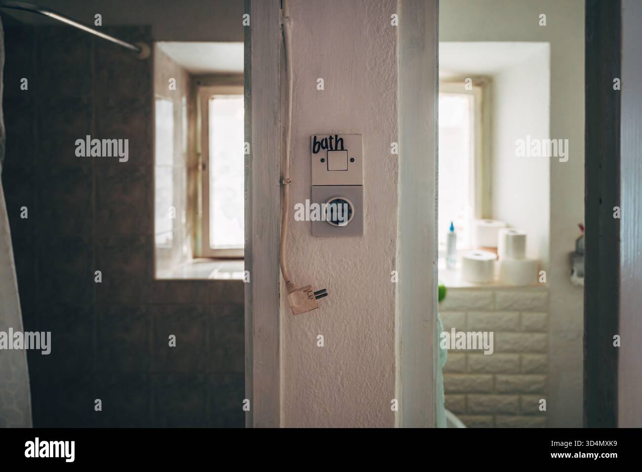 Vintage bathroom light switch with handwritten label "BATH" and old electricity socket, rustic aged bathroom interior detail. Selective focus. Stock Photo