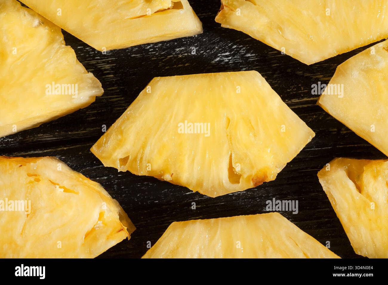 sliced pineapple on black wood background top view Stock Photo