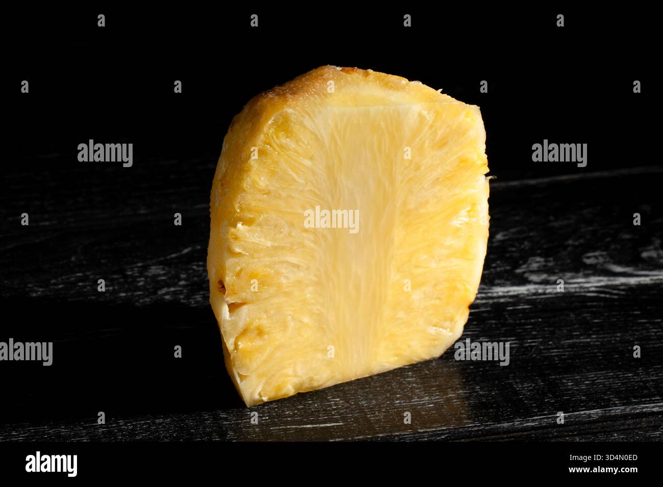 peeled sliced pineapple on black wood background Stock Photo