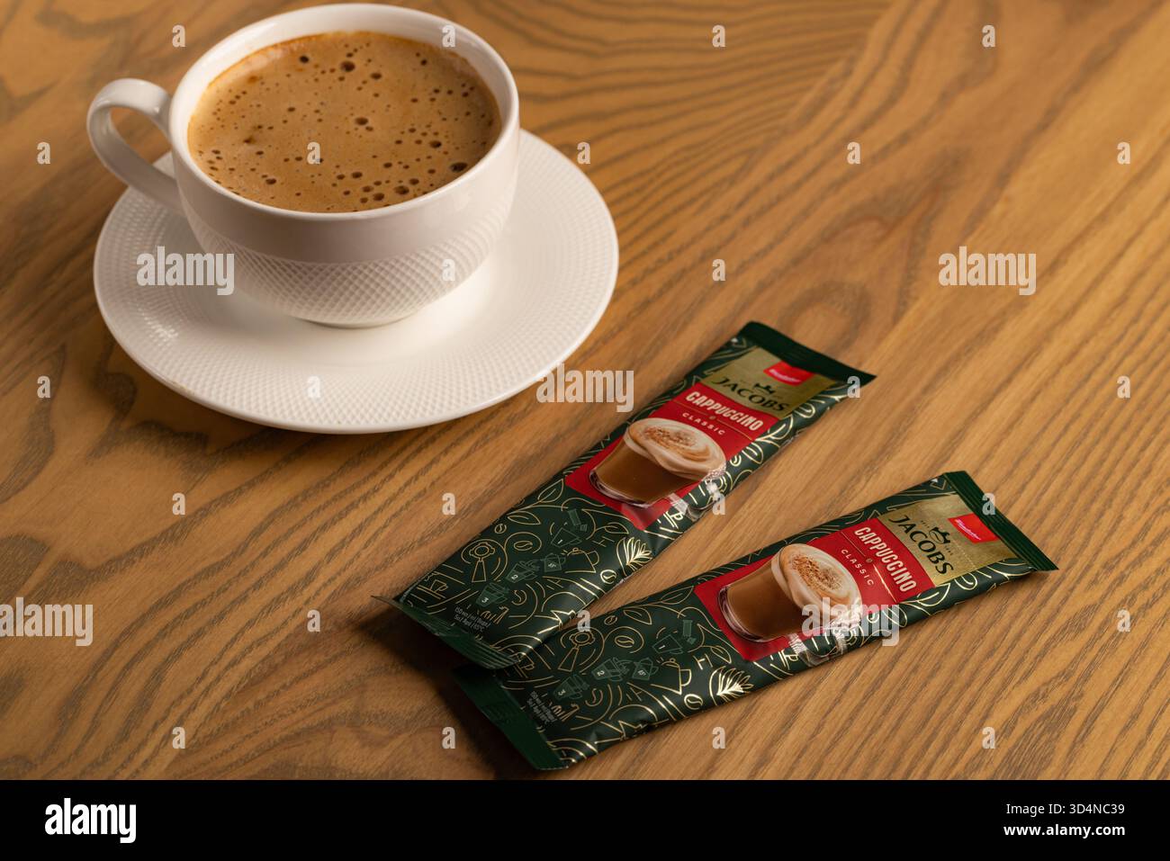 Lviv, Ukraine - November 11, 2025: Overhead View of Hot Cappuccino Cup and Jacobs Instant Sachets Stock Photo