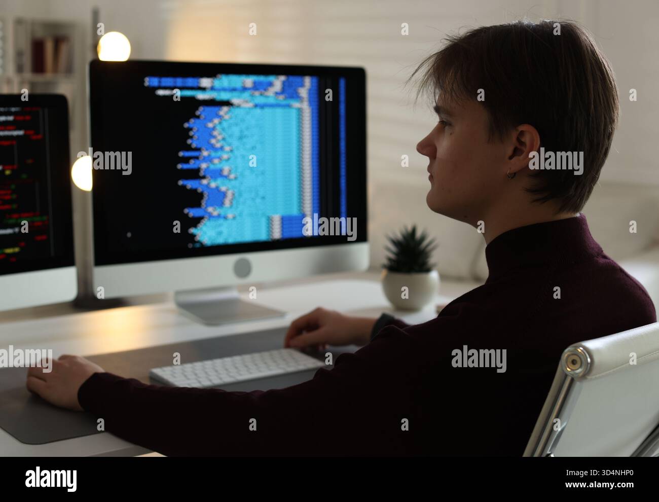 Programmer working on computer with dual monitors at white table in office Stock Photo