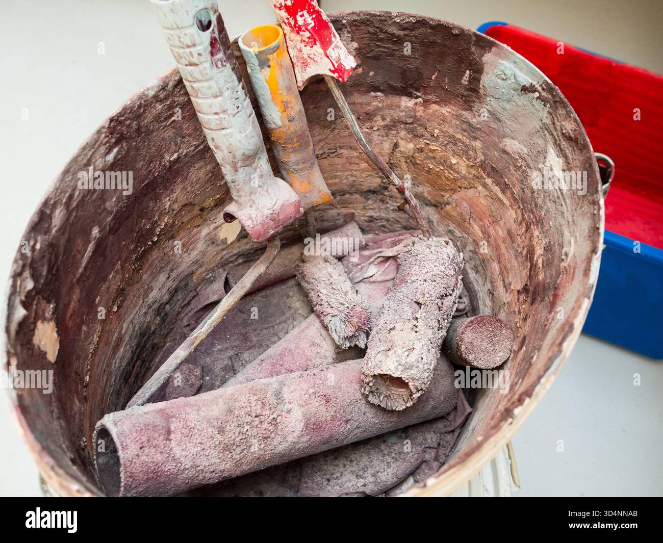few dried used paint rollers in plastic bucket Stock Photo