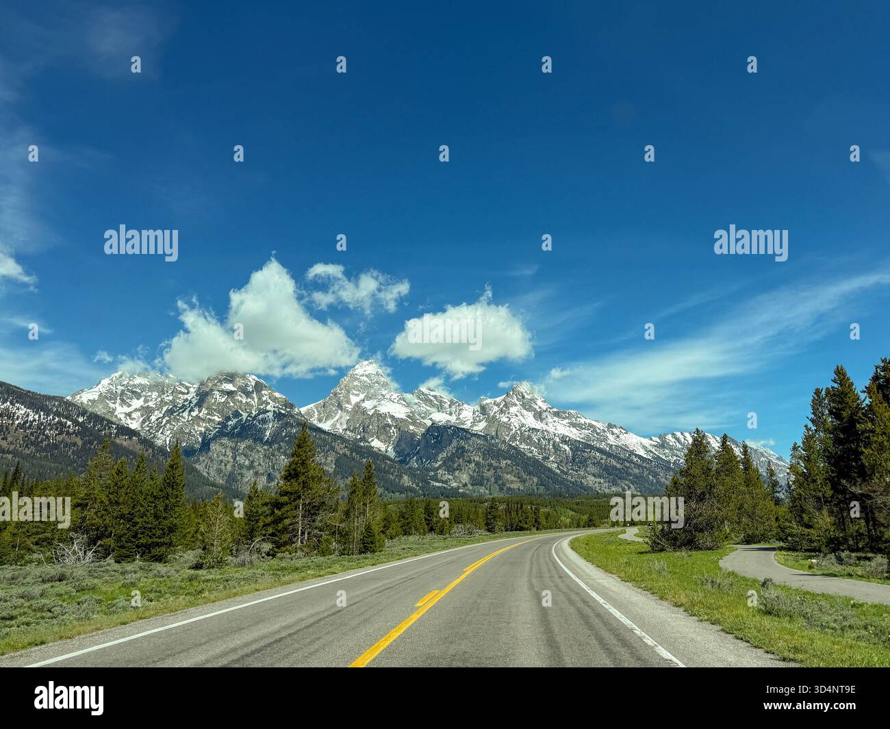 Scenic landscape view of a snow capped mountains from a car driving on a road through the Grand Teton national Park. No people. - Smartphone Captured Stock Image