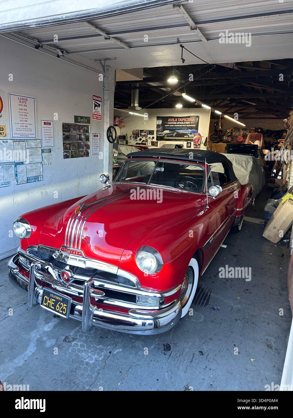 Red 1950s Pontiac convertible in auto upholstery workshop, California - Smartphone Captured Stock Image