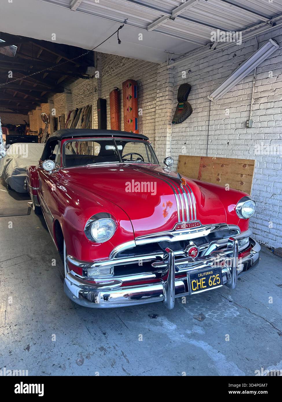 Red 1950s Pontiac convertible in auto upholstery workshop, California - Smartphone Captured Stock Image