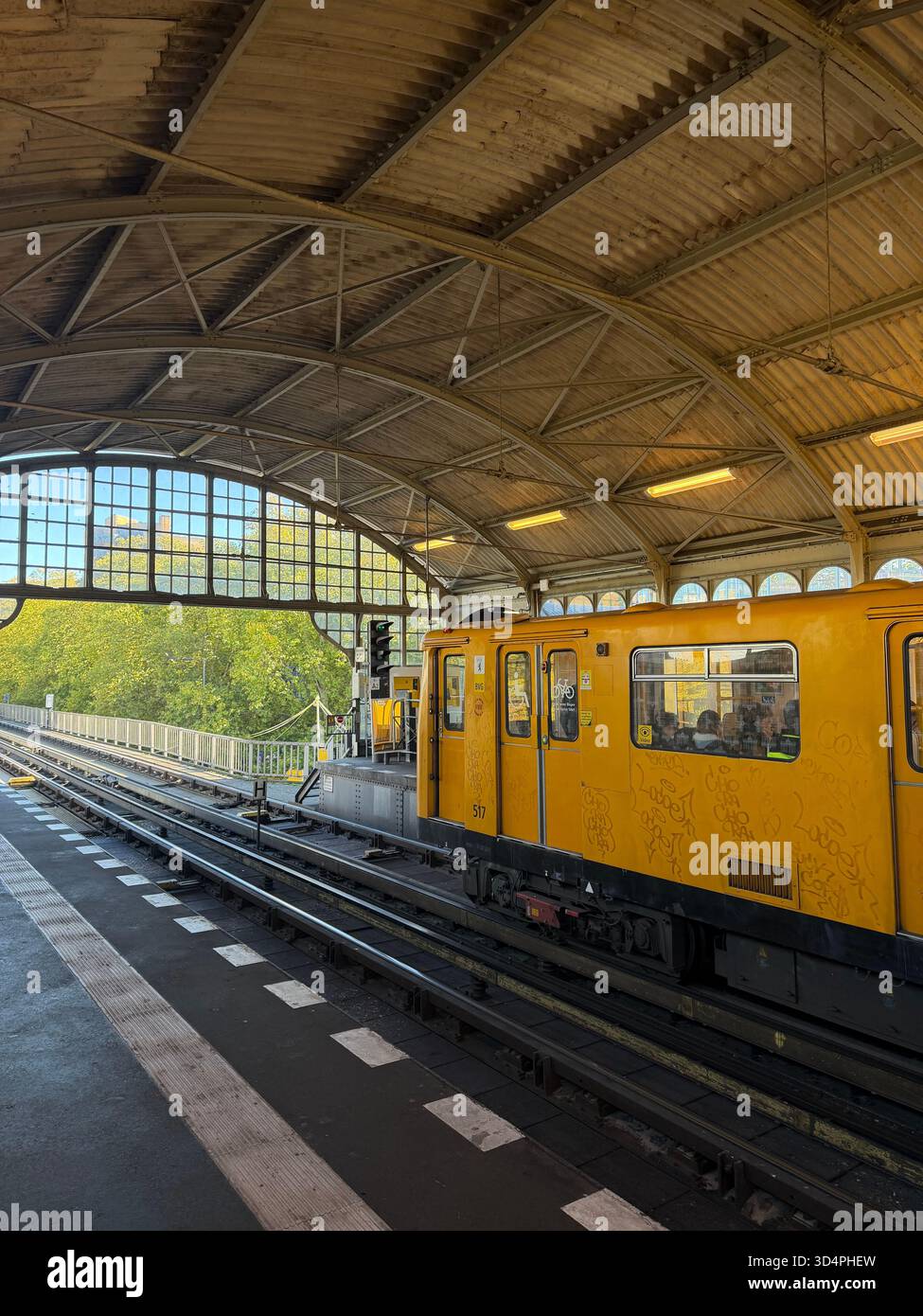Yellow metro train standing at an elevated urban station platform under a steel-and-glass roof. - Smartphone Captured Stock Image