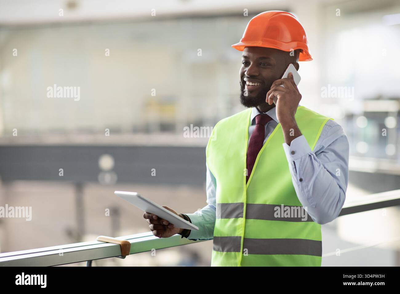 African american architect having phone conversation, using pad Stock Photo