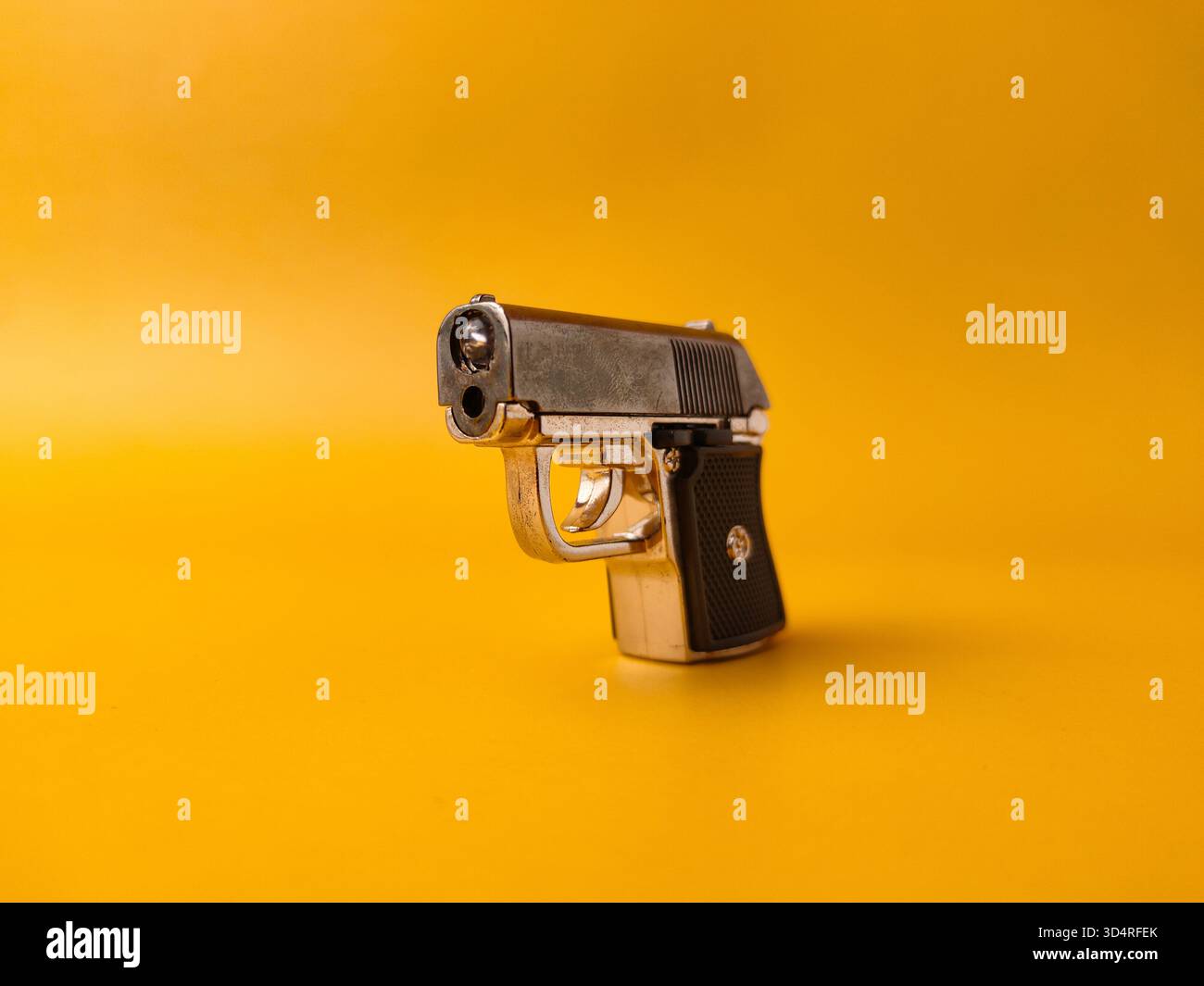 A small handgun is on a yellow background. Stock Photo
