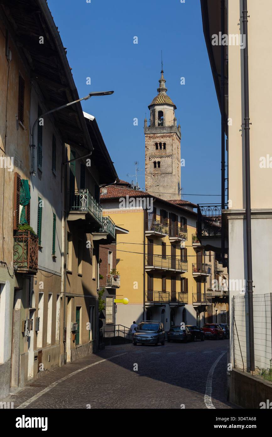 Beautiful evening light on the mainroad (Via Roma), as it passes historic houses and a church in Masserano, Biella Province, Italy. Copy space. - Stock Image
