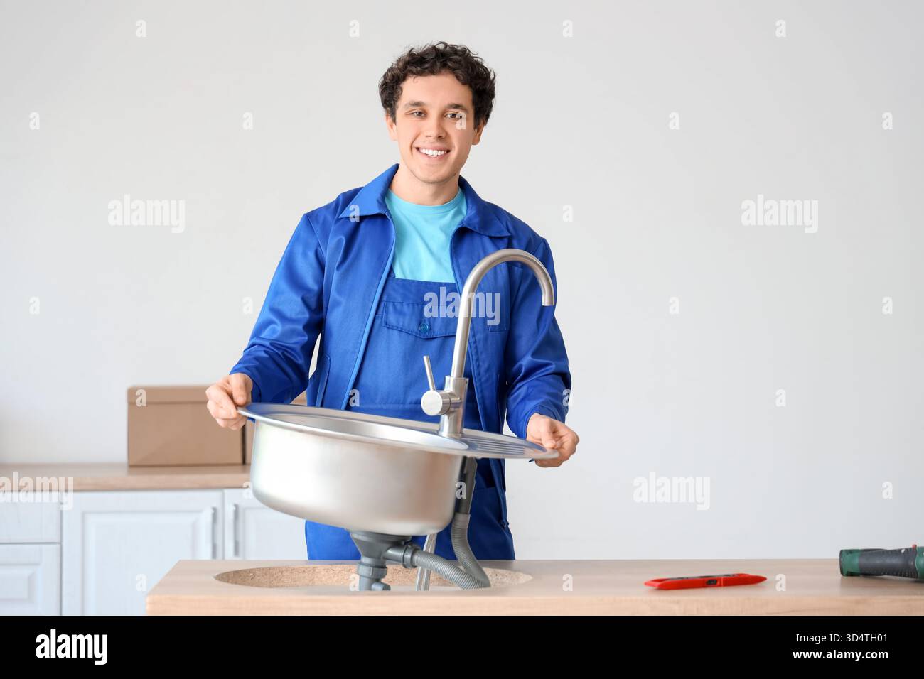 Male worker installing sink in kitchen Stock Photo