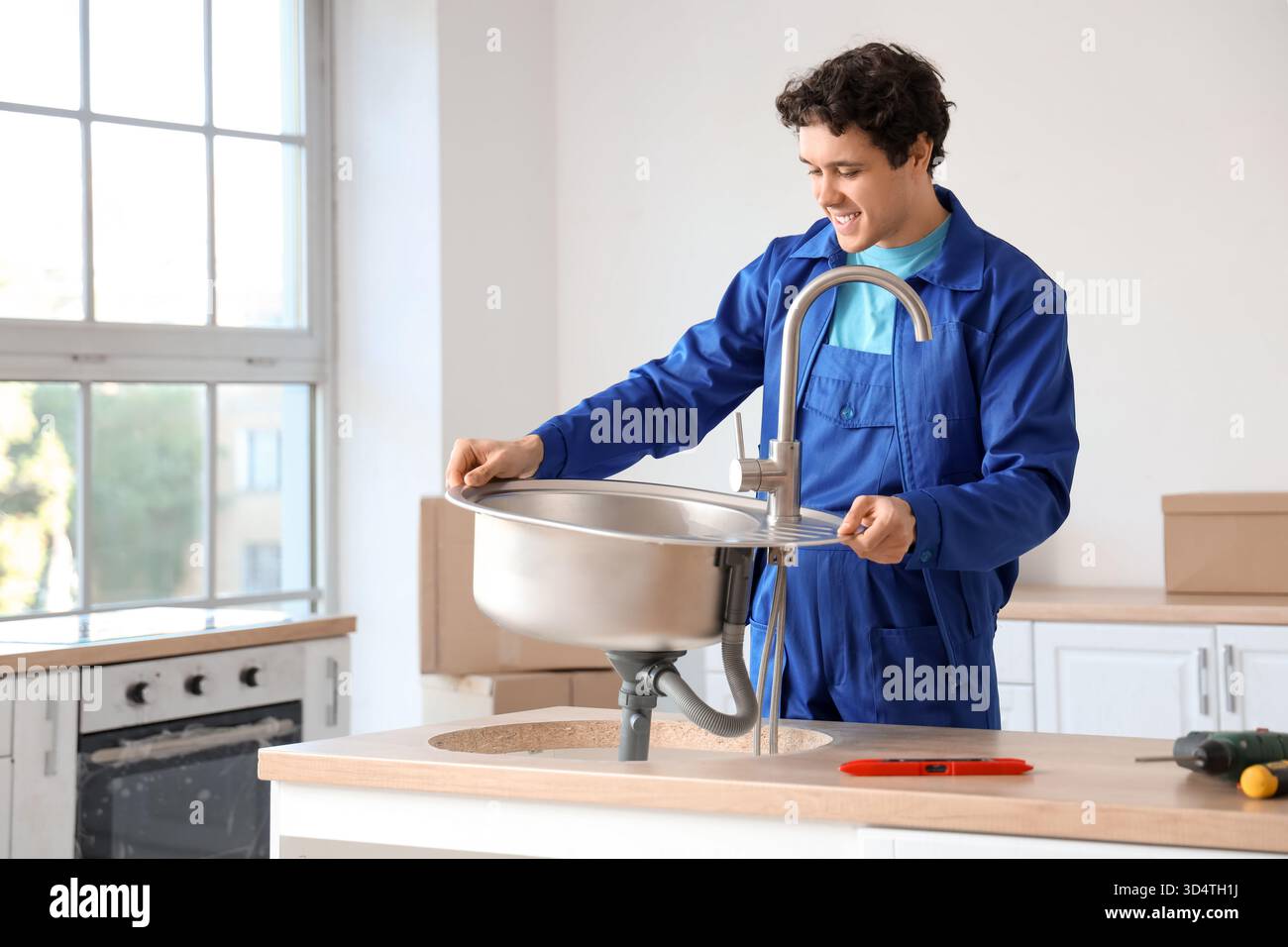 Male worker installing sink in kitchen Stock Photo