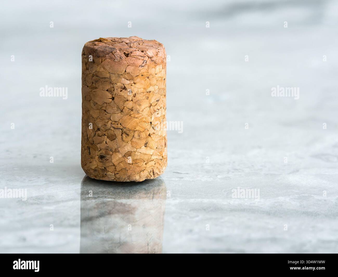 Wine cork standing on polished marble surface with reflection. Stock Photo