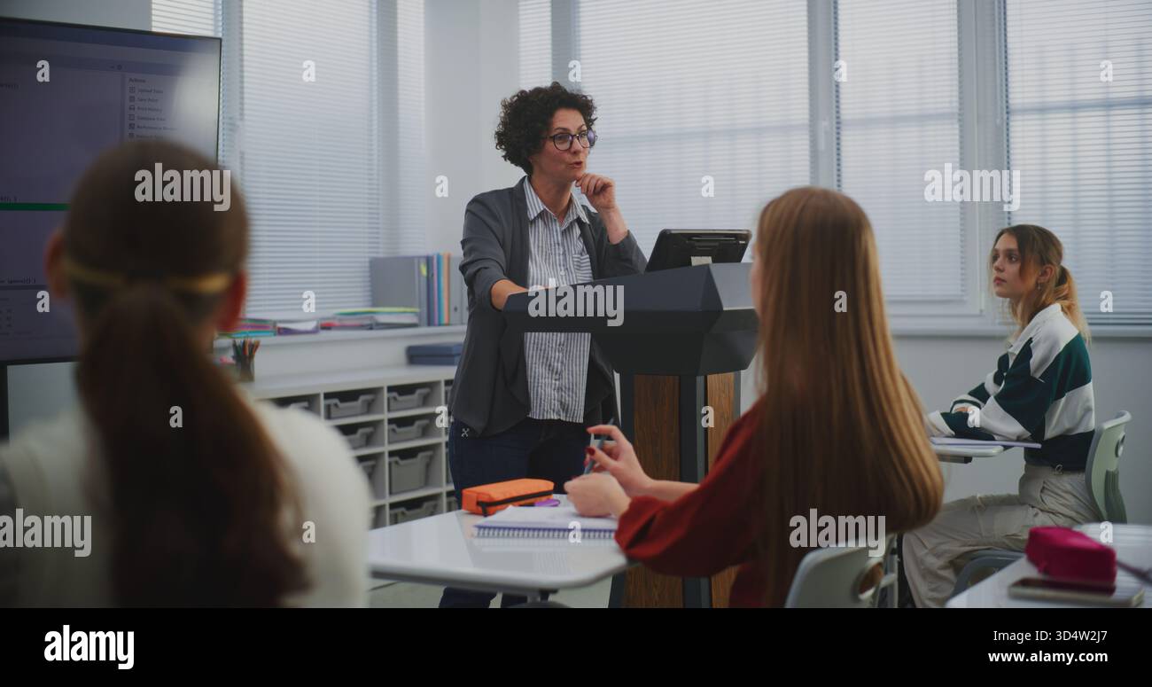 Female Educator in Computer Programming Class Presents Software Code on Smartboard, Engaging Students in Discussion. Concept STEM Education, Interactive Learning, and Innovation in Teaching Methods. Stock Photo