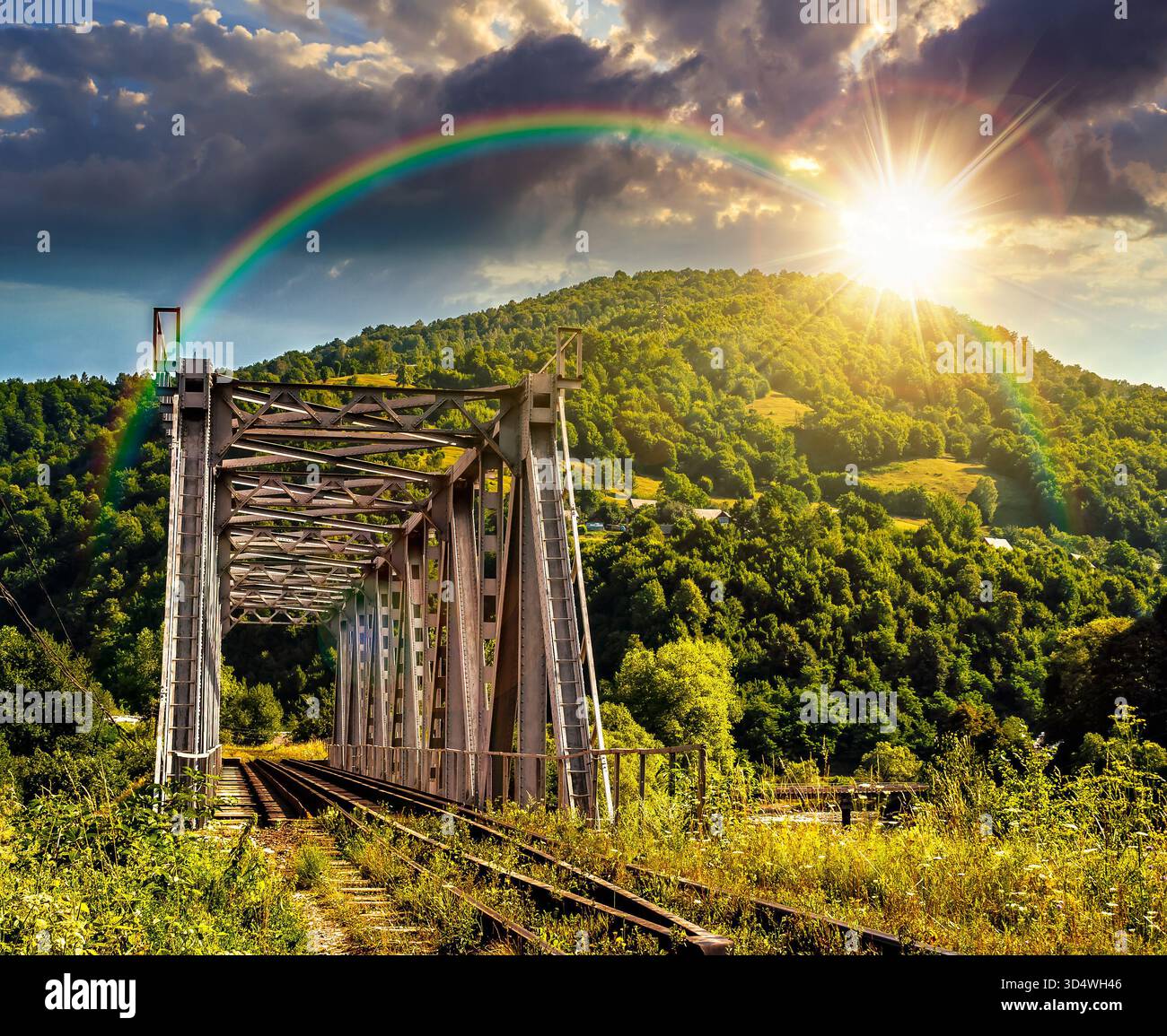 old metal rail road bridge in rural area in mountains at sunset. journey through beautiful landscape in evening light. transportation or retro technol Stock Photo