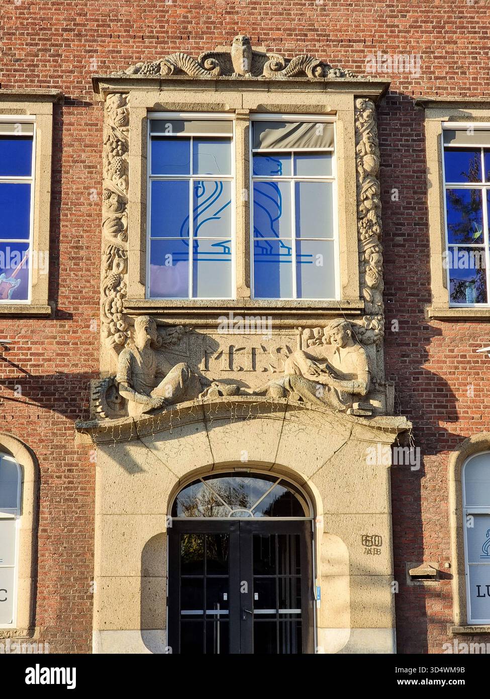 Decorated window above entrance of monumental building of former Middelbare Technische School (MTS), now Luzac College in Eindhoven The Netherlands - Smartphone Captured Stock Image