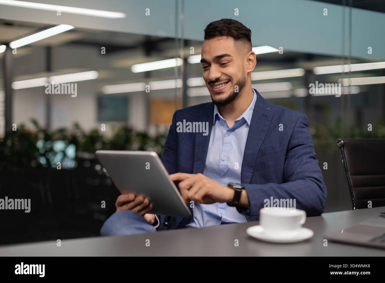 Happy Middle Eastern Businessman Using Digital Tablet in Modern Office Environment Stock Photo