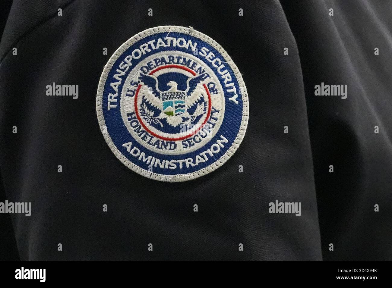 A TSA agent wears a Transportation Security Administration badge while ...