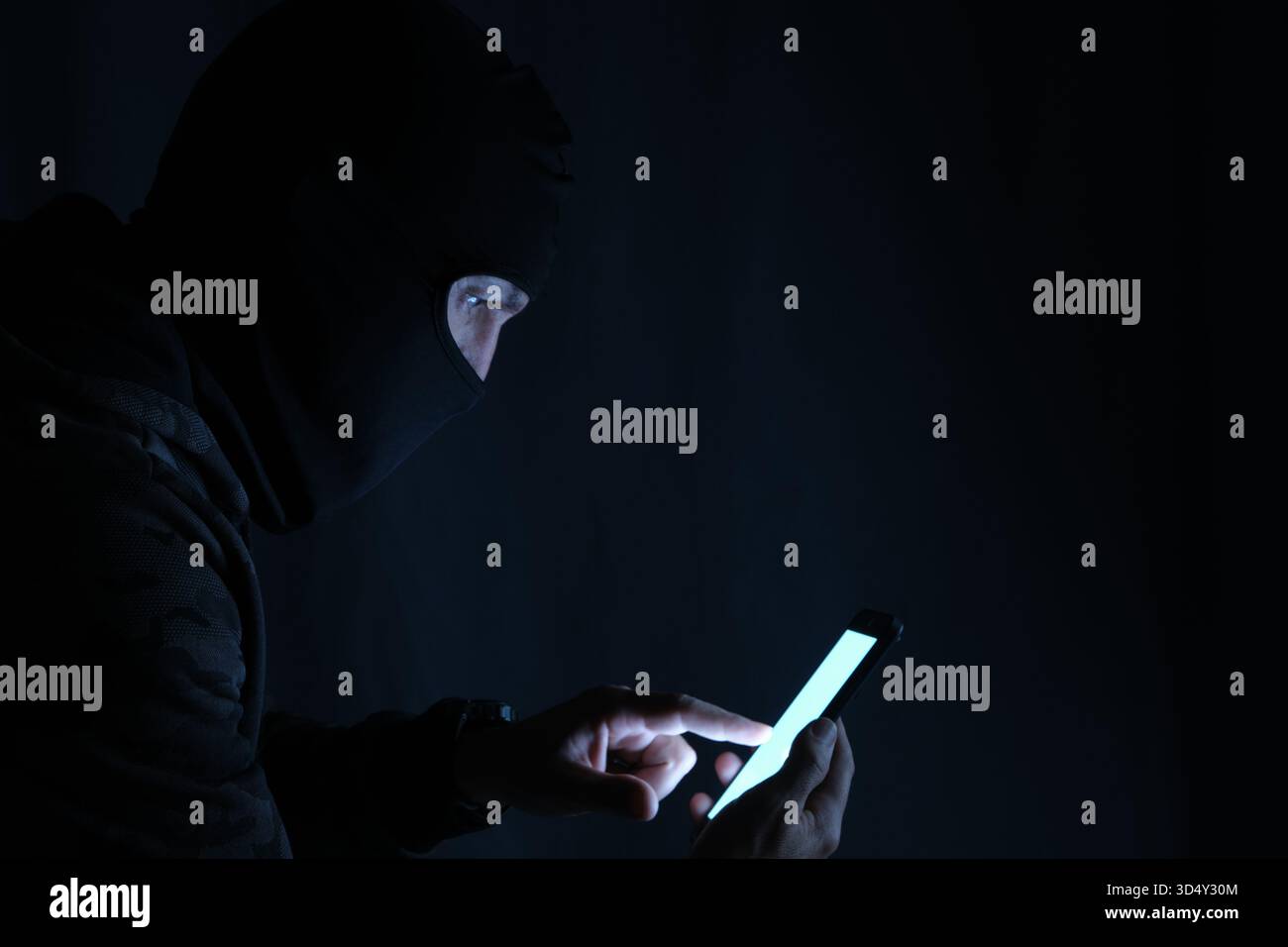 Hacker using mobile phone in dark room, cyber security concept Stock Photo