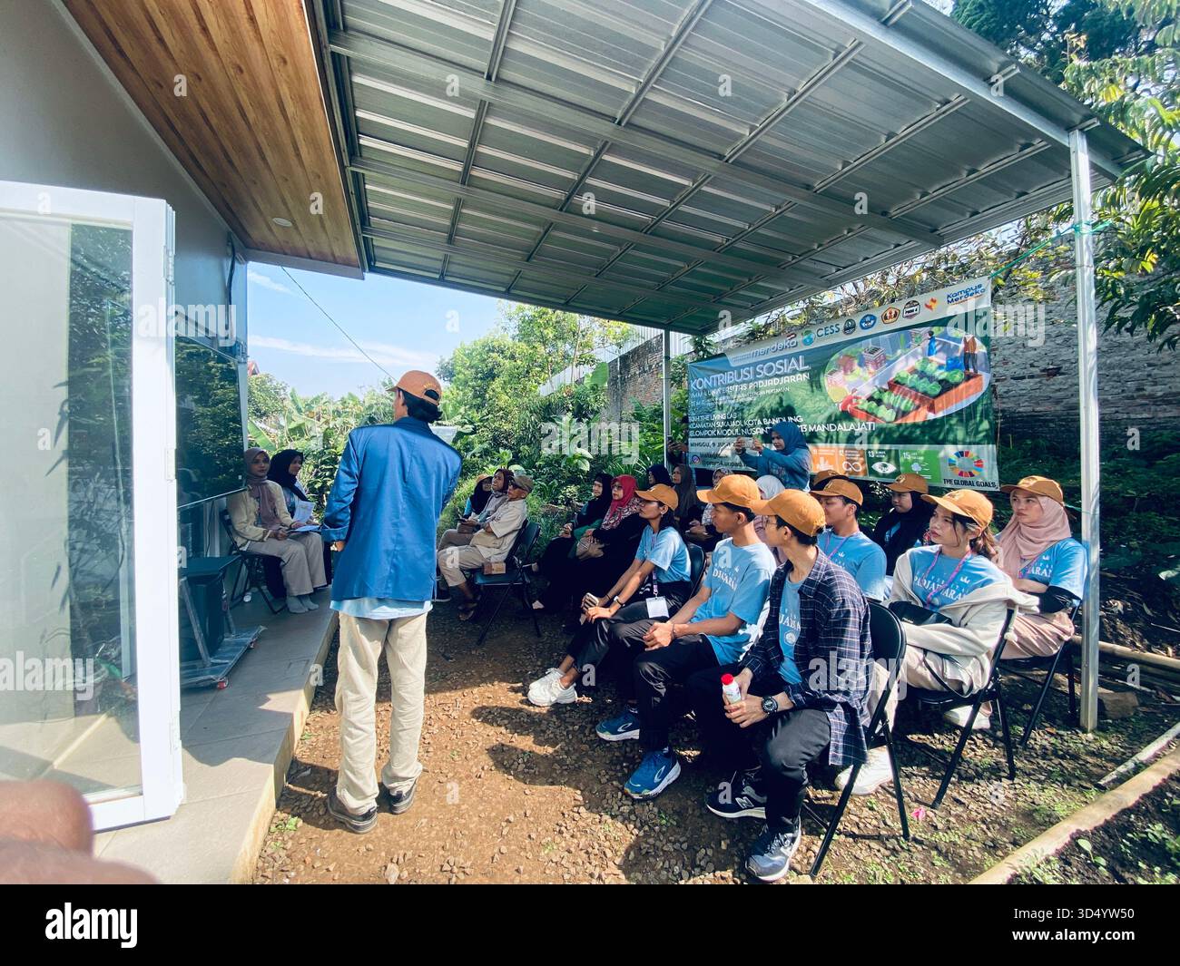 A group of students, lecturers, and community members participating in the 'Kontribusi Sosial' (Social Contribution) - Smartphone Captured Stock Image