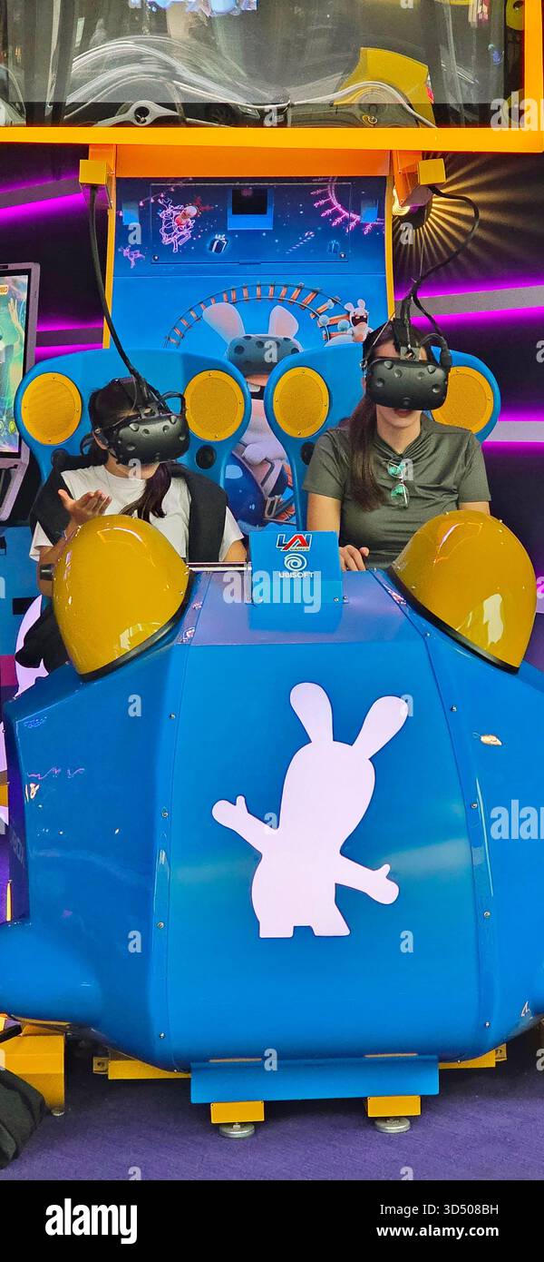 Berlin, Germany - September 22, 2025: Two women are experiencing a virtual reality ride in a vibrant gaming booth. - Smartphone Captured Stock Image