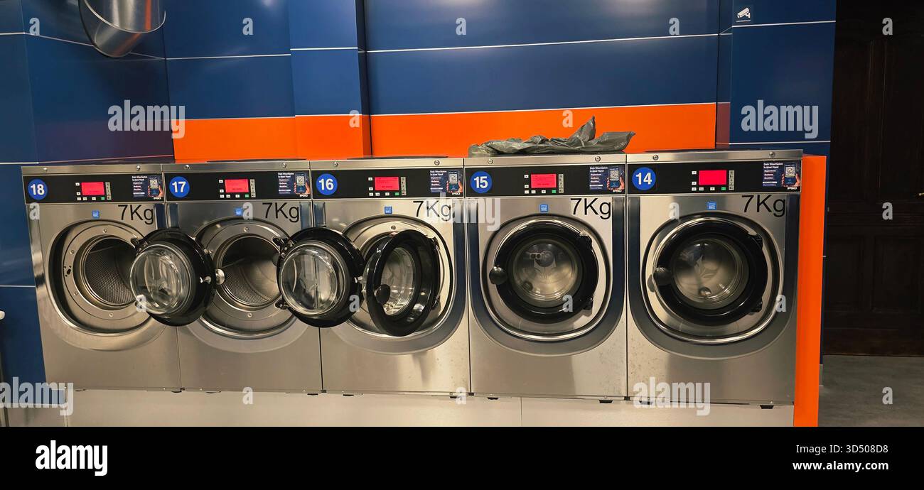 Berlin, Germany - September 25, 2025: Modern laundromat features multiple washing machines in vibrant colors and sleek design. - Smartphone Captured Stock Image