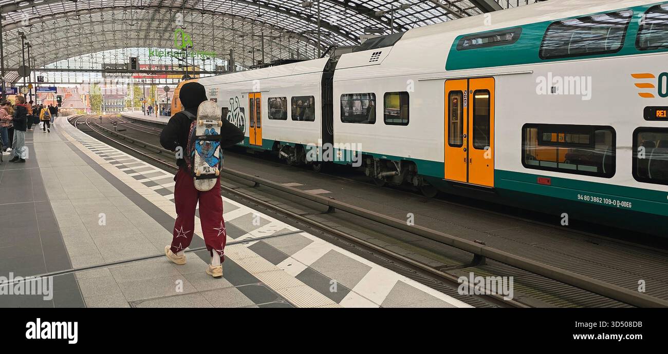 Berlin, Germany - September 25, 2025: Individual stands at railway station, waiting for train amidst modern architecture and urban design. - Smartphone Captured Stock Image