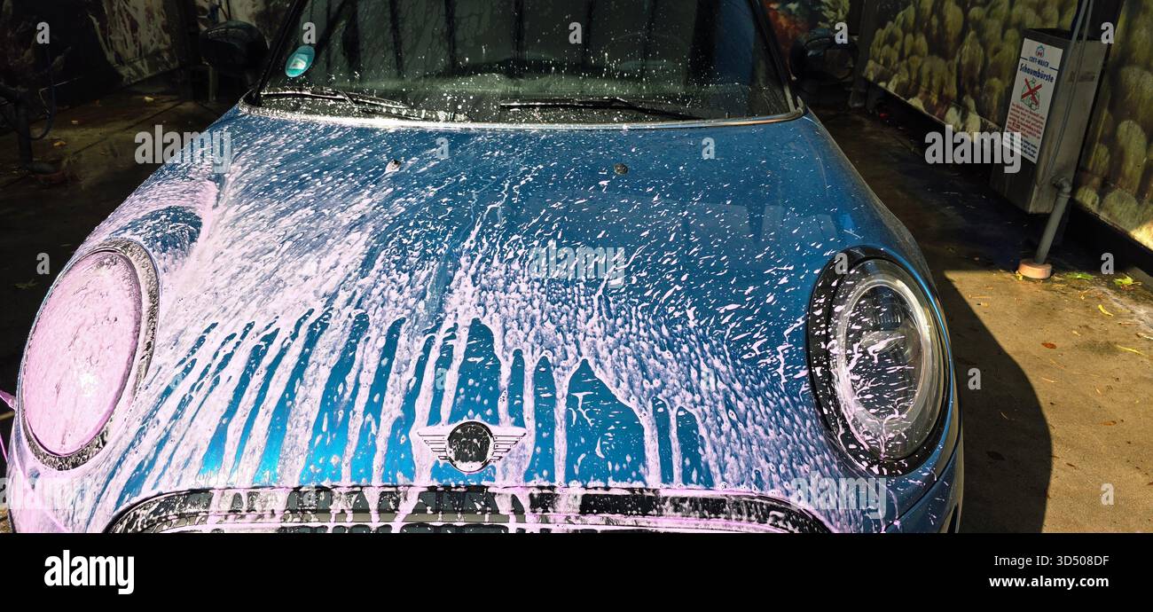 Berlin, Germany - September 27, 2025: Blue Mini Cooper is covered in soap while being washed at a car wash. - Smartphone Captured Stock Image