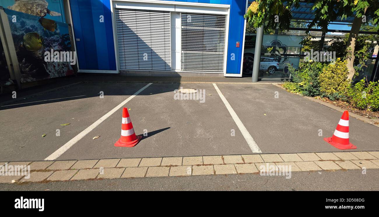 Berlin, Germany - September 27, 2025: Parking area features traffic cones marking empty spaces by building entrance. - Smartphone Captured Stock Image