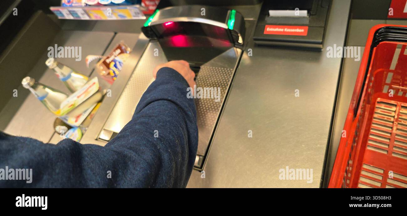 Berlin, Germany - September 27, 2025: Hand is scanning items at self-checkout with bright display lights illuminating the area. - Smartphone Captured Stock Image