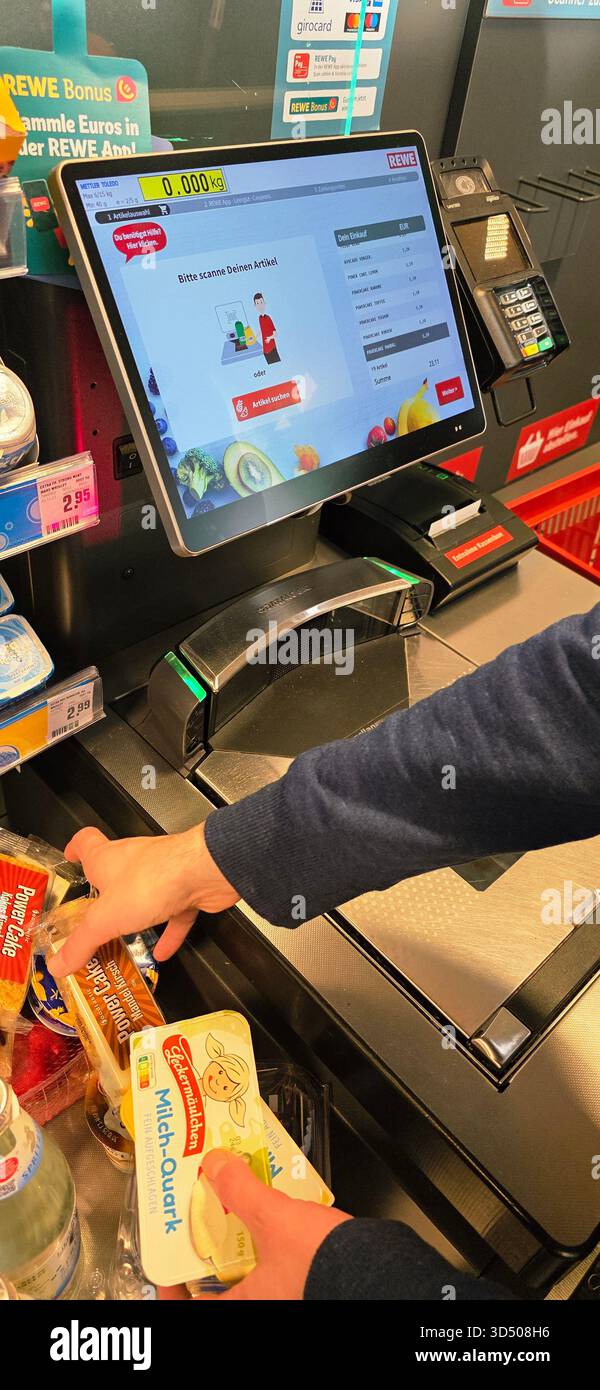 Berlin, Germany - September 27, 2025: User at self-checkout kiosk scanning groceries with touchscreen interface. - Smartphone Captured Stock Image